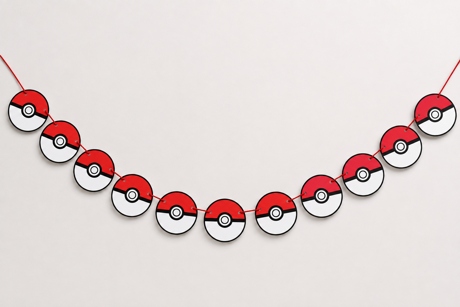 Guirlanda decorativa com círculos em padrão Pokébola vermelha, branca e preta em fio vermelho