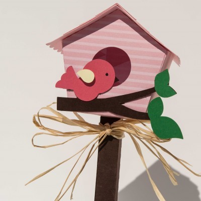 Casa de pássaros decorativa em papel rosa com pássaro cor-de-rosa e folhas verdes