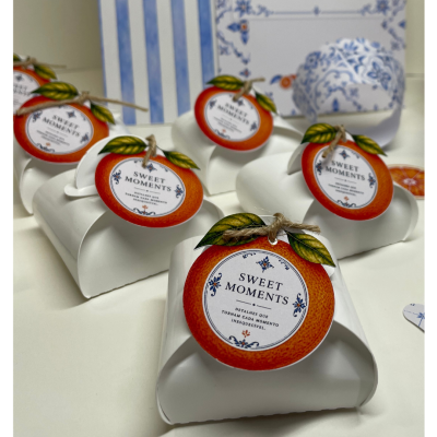 Embalagens brancas com etiquetas redondas de laranja e texto SWEET MOMENTS num fundo branco.