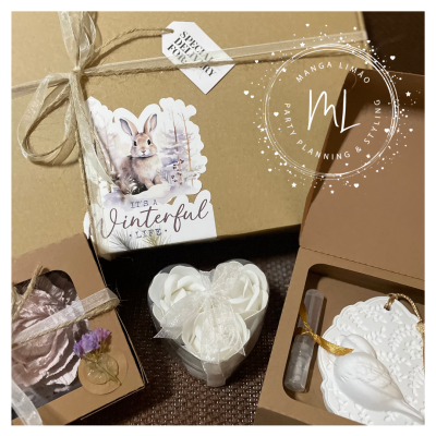 Conjunto de presentes em caixas castanhas com velas, sabonetes e decoração com tema invernal e etiquetas