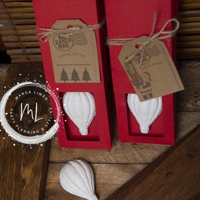 Dois enfeites de balão branco em caixas vermelhas com etiquetas de cartão pardo decorativas