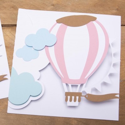 Cartão com balão de ar quente, nuvens e sol em relevo