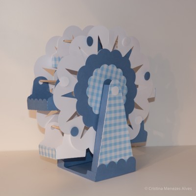 Roda gigante decorativa em cartão azul, branco e bege com padrões xadrez e círculos