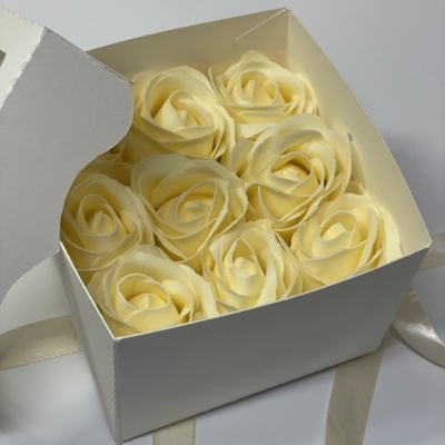 Caixa branca aberta com sete rosas artificiais creme dentro