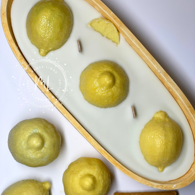 Vela decorativa com limões amarelos realistas numa base oval de madeira clara e cera branca