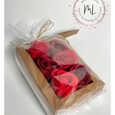 Caixa de rosas artificiais vermelhas em embalagem transparente com cordão de sisal