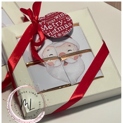 Caixa branca com quatro chocolates quadrados decorados com imagem do Pai Natal, fita vermelha e etiqueta Merry Christmas