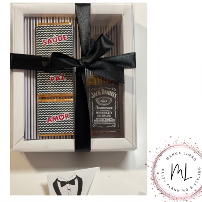 Caixa de presente branca com laço preto contendo mini garrafa Jack Daniel's e três chocolates com texto Saúde, Paz, Amor