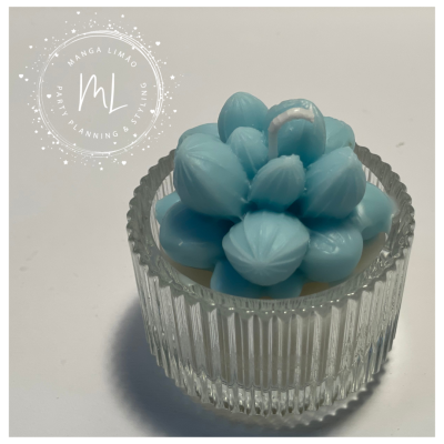 Vela azul em base de vidro transparente com textura, sobre fundo branco