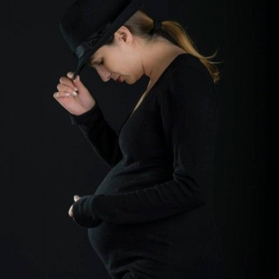 Mulher grávida de perfil com vestido e chapéu pretos