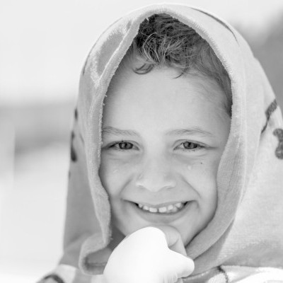 criança sorridente com toalha na cabeça ao ar livre