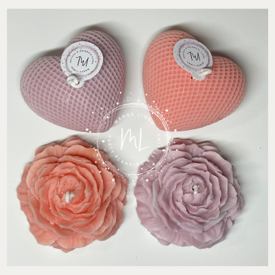 Quatro velas decorativas, duas em forma de coração rosa e coral e duas em forma de rosa lilás e coral.