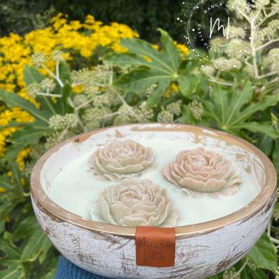Taça decorativa com flores esculpidas flutuando em líquido branco num ambiente natural