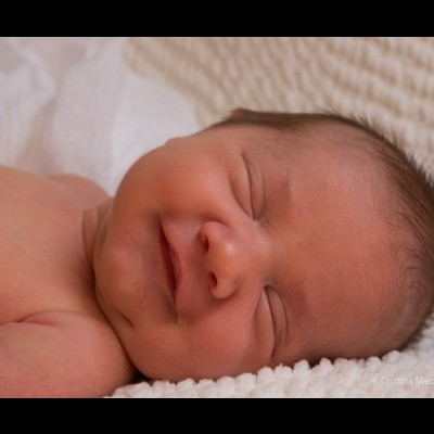 Recém-nascido a dormir sobre manta branca texturizada