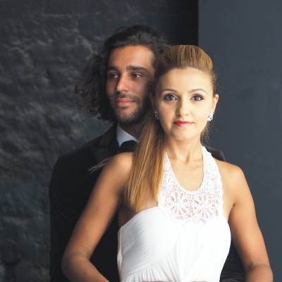 Casal vestido formal com parede cinza escura ao fundo