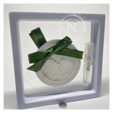Quadro decorativo branco com ornamento circular e laço verde junto a frasco spray transparente