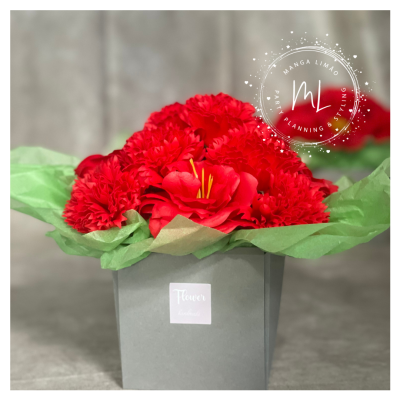 Arranjo floral vermelho em vaso cinza com etiqueta 'Flower handcrafted'