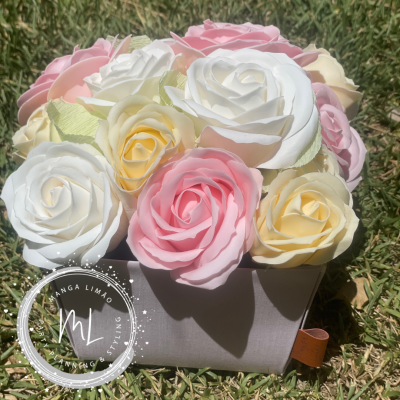 Arranjo de flores artificiais coloridas em caixa cinza sobre relva