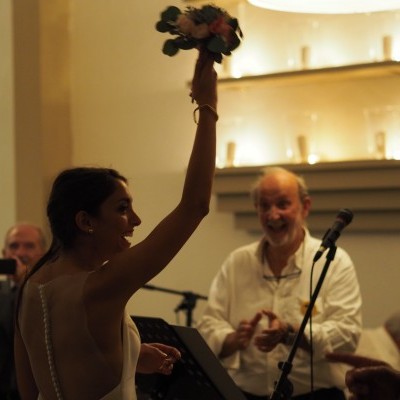 Mulher de vestido branco segura ramo de flores em ambiente festivo interior