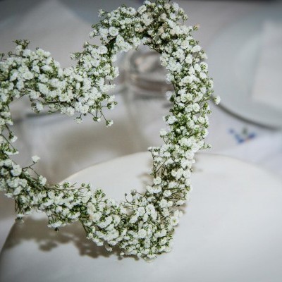 Arranjo de flores brancas em forma de coração sobre cadeira branca