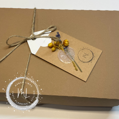 Caixa castanha com etiqueta decorada com flores secas e selo 'ml'