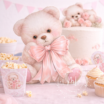 Ursinho de pelúcia branco com laço rosa em ambiente de festa com pipocas, cupcakes e bolo decorado