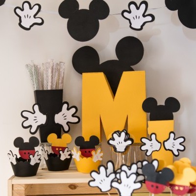 Decoração de festa com tema Mickey Mouse com recortes coloridos e copos decorativos