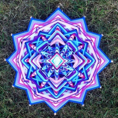 Mandala colorida de fios entrelaçados em forma geométrica sobre relva