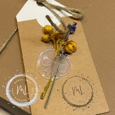 Etiqueta decorativa com flores secas e selo de resina sobre embalagem castanha