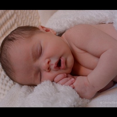 Bebé recém-nascido a dormir enrolado numa manta branca macia