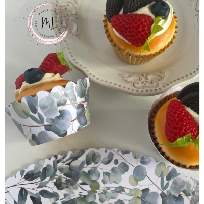 Cupcakes decorados com fruta e bolacha Oreo sobre pratos brancos e forminhas com padrão de folhas