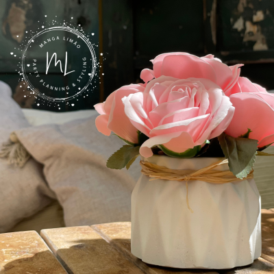 Vaso branco com flores artificiais cor de rosa sobre mesa de madeira