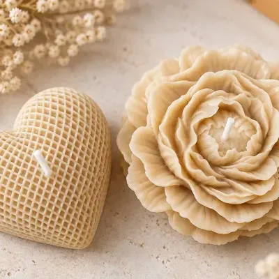 Velas decorativas em forma de coração e flor bege sobre superfície clara com flores secas