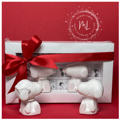 Figuras decorativas brancas de Snoopy e caixa branca com fita vermelha.