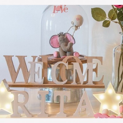Letras de madeira formando WELCOME e RITA com estrelas luminosas e elefante decorativo
