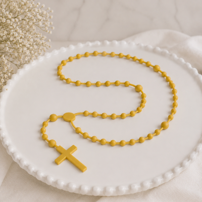 Terço amarelo com cruz sobre placa branca decorativa