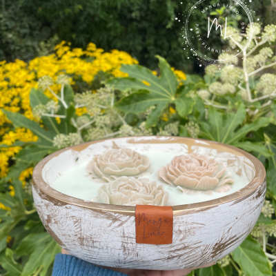 Taça decorativa azul e bege com flores esculpidas, em fundo de plantas e flores amarelas