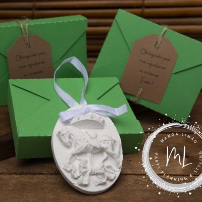 Embalagens verdes com etiquetas castanhas e decoração branca em relevo com laço, sobre superfície de madeira