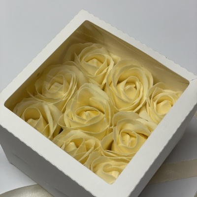 Caixa branca com flores amarelo-pálido em tecido visíveis pela tampa transparente