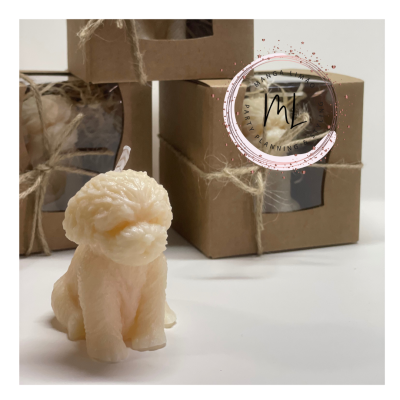 Vela em forma de cão bege com caixas de cartão no fundo