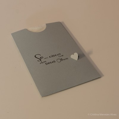 Envelope cinzento com texto em português e um pequeno coração branco