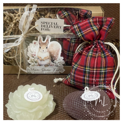 Caixa de presente com laço e etiquetas decorativas, duas velas em formatos decorativos em frente