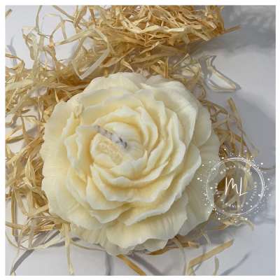 Vela em forma de flor branca com palha seca ao redor e selo ML