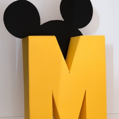 Letra grande amarela com silhueta preta de orelhas arredondadas atrás