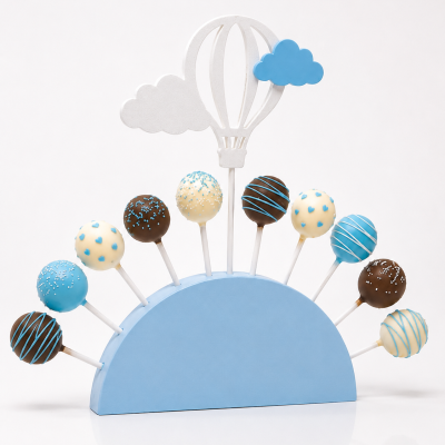 Cake pops coloridos em suporte azul com decoração de balão e nuvens