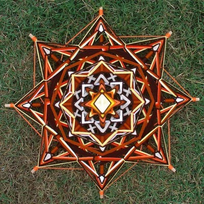 Objeto decorativo em forma de estrela com fios coloridos sobre relva