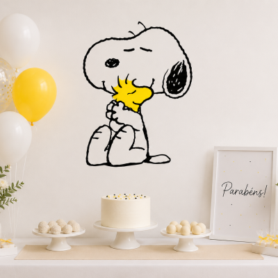 Decoração de festa com bolo branco, balões amarelos e brancos, vasos com flores e quadro Parabéns! com Snoopy a abraçar Woodstock no fundo