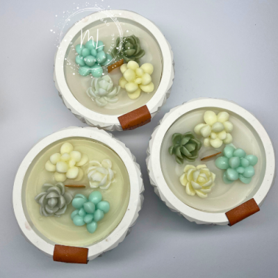 Velas decorativas com flores coloridas em recipientes brancos redondos com detalhe em pele