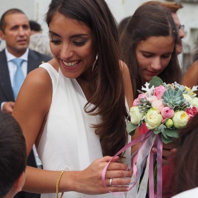Mulher com vestido branco a segurar bouquet de flores coloridas em evento exterior