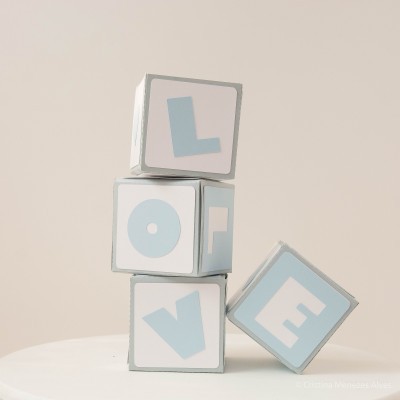 Quatro blocos brancos com letras azuis formando a palavra LOVE